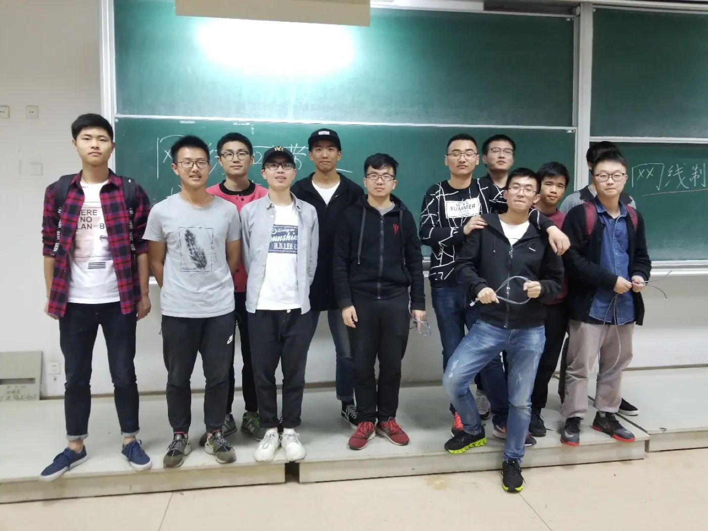 十余名学生在黑板前站成一排合影，多数人手里举着刚做好的网线，背后黑板上写着“网线制”几个粉笔字
