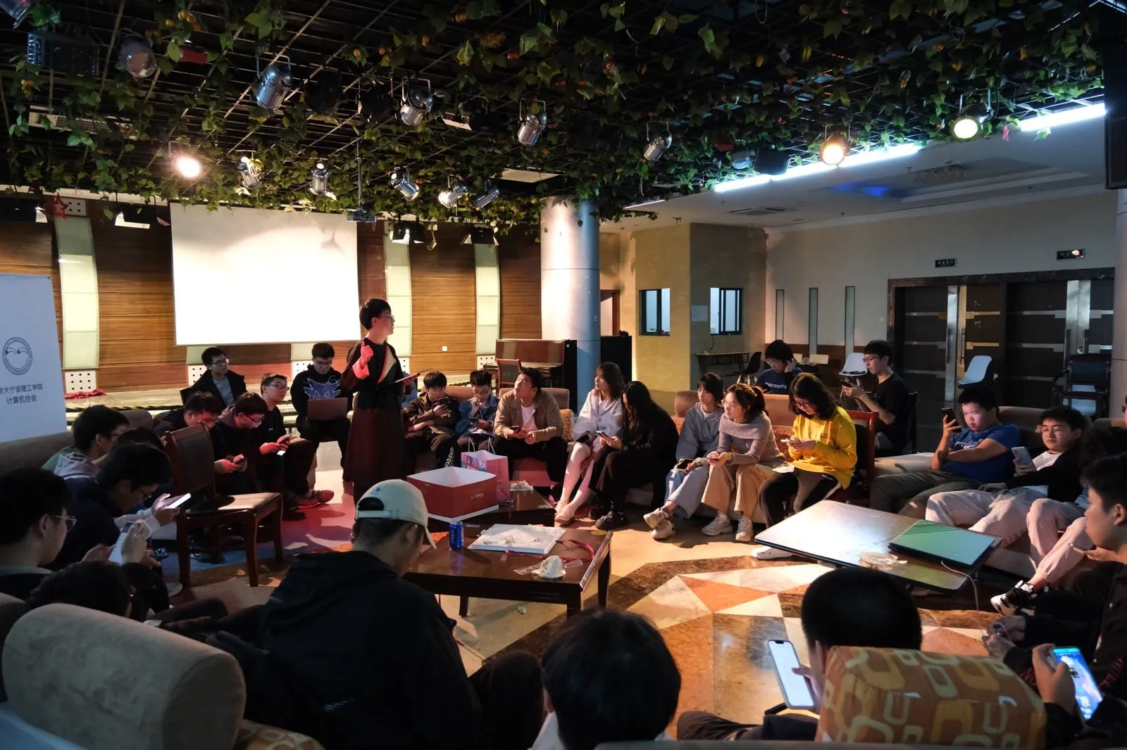 2023 年秋季迎新大会，成员围坐在沙发与茶几旁