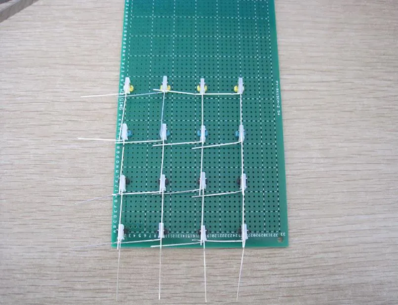 同一块绿色万用板,16 颗整形好的 LED 已夹在排针之间排成四行四列,引脚横竖相连成网格