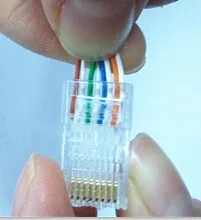 手指捏住一枚水晶头，八根排好序的芯线正插入其中，侧面可见每根都顶到了头部